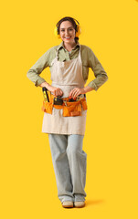 Female worker with bag of tools on yellow background