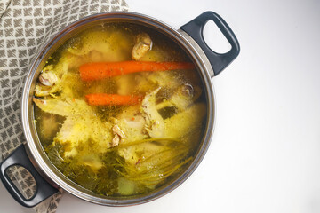 Using a metal pot to cook chicken broth with meat and vegetables.