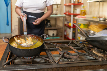 Chef removing fried wonton from a pan filled with oil