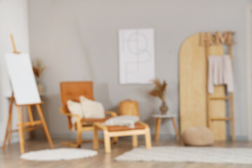 Blurred view of stylish living room with poster, easel and armchair