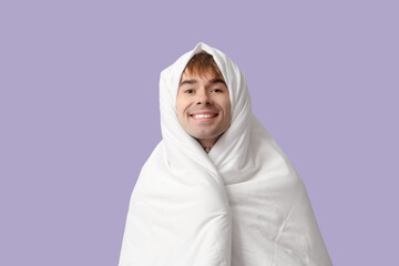 Handsome young man with blanket on lilac background