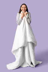 Pretty young woman with blanket on lilac background