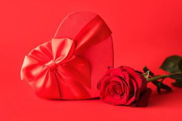 Beautiful rose flower and heart-shaped gift box on red background. Valentine's Day celebration
