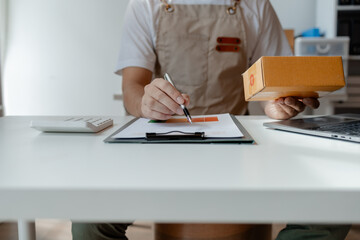 owner of an online store packs products into parcel boxes based on orders from online sales sites,...
