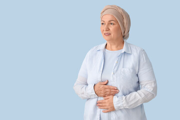 Smiling mature woman after chemotherapy on blue background. Stomach cancer concept