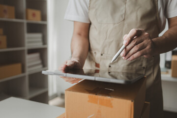 Obraz premium tablet are being used to do various activities to promote sales to stores, owner of an online store packs products into parcel boxes based on orders from online sales sites.