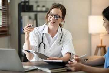 Female doctor sitting at work looking at the history of patients in the clinic or in the hospital