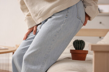 Mature woman with hemorrhoids and cactus on sofa at home, closeup