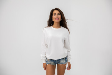 Beautiful girl in shorts and a white sweatshirt posing on a white background