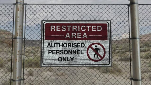 High quality 3D CGI render with a smooth dollying-in shot of a chainlink fence at a high security installation in a desert scene, with a Restricted Area - Authorised Personnel Only sign
