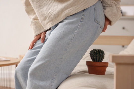 Mature woman with hemorrhoids and cactus on sofa at home, closeup