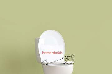 Toilet bowl with word HEMORRHOIDS and barbed wire on green background