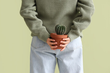 Mature woman with cactus on green background, back view. Hemorrhoids concept © Pixel-Shot
