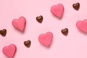 Obraz premium Tasty heart-shaped macaroons and chocolate candies on pink background. Valentine's Day celebration