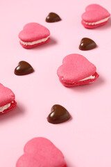 Obraz na płótnie Canvas Tasty heart-shaped macaroons and chocolate candies on pink background. Valentine's Day celebration