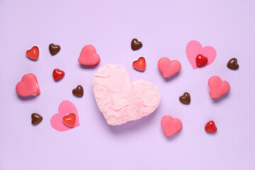 Tasty candies with candles and heart-shaped fluffy pillow on purple background. Valentine's Day celebration