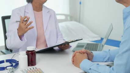 An elderly Asian male patient answers questions from an elderly female doctor. health advice and discuss comprehensive health care in a healthcare environment. Health insurance concept.