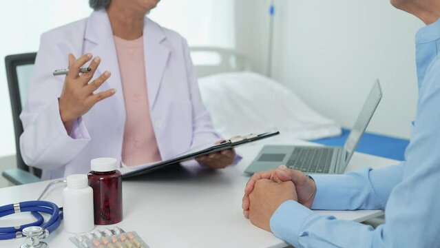 An elderly Asian male patient answers questions from an elderly female doctor. health advice and discuss comprehensive health care in a healthcare environment. Health insurance concept.