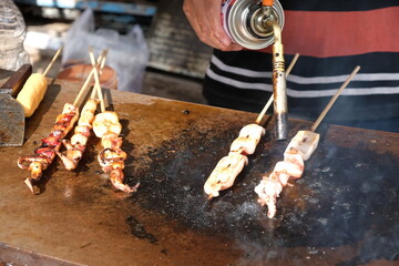 food sellers are grilling squid with flames from small gas cylinders. grilled squid. cumi-cumi...