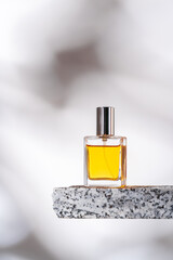 Perfume bottle on granite stones against white background with shadows