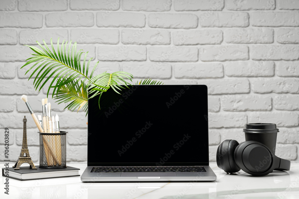 Sticker Laptop with black screen on desk against white brick wall