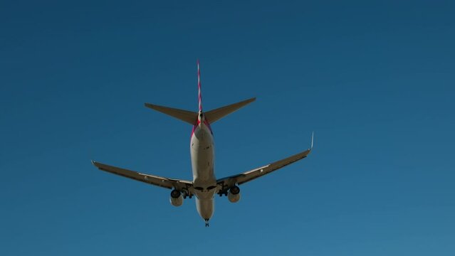 Plane flying over head, landing at airport at sunny day time. Slow motion shot