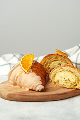 Glazed croissant with dried orange on wooden board
