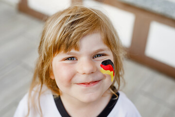 Little blond preschool girl watching soccer football cup game on public viewing. Happy joyful...