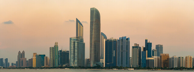 The corniche and skyline of Abu Dhabi after sunset, with futuristic and modern skyscrapers. Blue hour, pink sky.