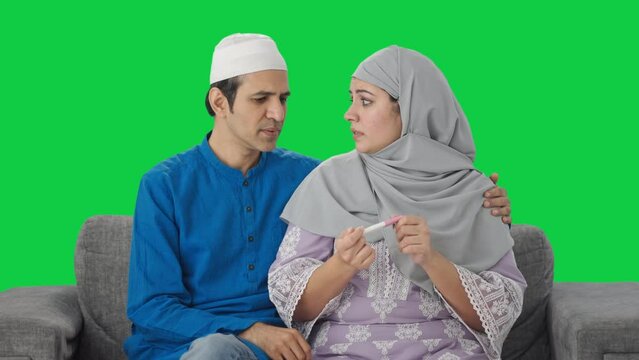 Stressed Muslim couple checking pregnancy test Green screen