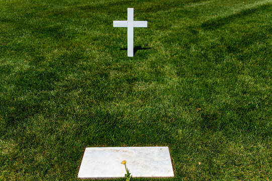 Tomb and white marble cross with flower at Arlington National Cemetery, a military cemetery in Washington DC, the capital of the USA.