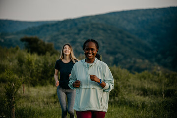 Black and Caucasian women jogging in unity, managing fitness goals on smartwatches