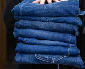 Trzymać stos niebieskich jeansów spodni w dłoniach 