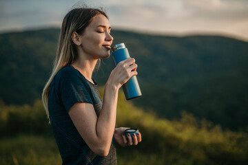 Fit Caucasian woman quenching her thirst with refreshing water after a vigorous outdoor jog