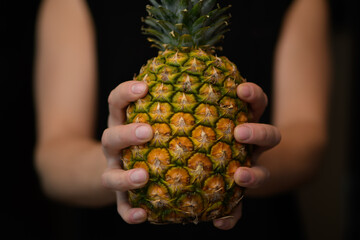 Mężczyzna trzyma w dłoni dojrzałego ananasa - obrazy, fototapety, plakaty