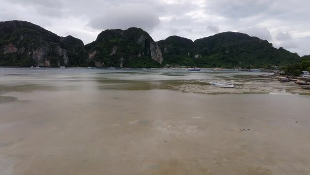 Drone footage from PhiPhi islands in Thailand footage of incredible Thai landscapes incredible nature with insane rocks, beaches, hills, ocean adn boats. 5 model man on a beach walking.