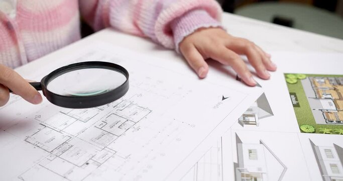 Architect at the construction site checks house plan documents with a pencil to check structural design, correctness, and construction strength.