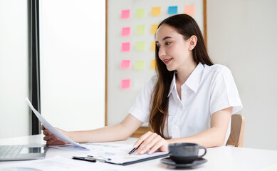 Asian businesswoman sit at their desks and calculate financial graphs showing results about their...
