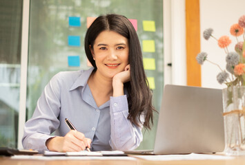 Asian businesswoman sit at their desks and calculate financial graphs showing results about their...