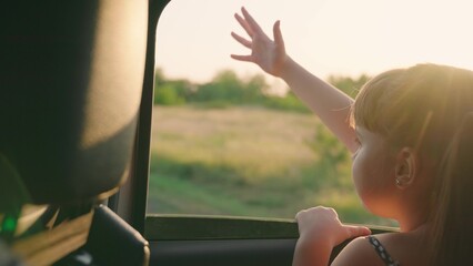 child girl face looks smiling from car out window, sun glare sunset, happy girl smiling from car...