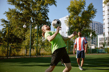 Male football player hitting ball with his chest training at street soccer field