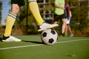 Closeup male foot in boots on soccer ball over green grass field