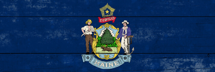 Maine State flag on a wooden surface. Banner of the grunge Maine State flag.