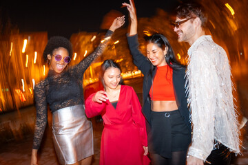 Multi-ethnic friends dancing in the street at night