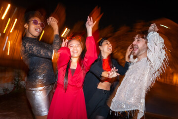 Happy friends partying and dancing in the city at night