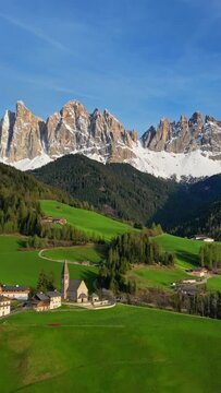 Spring landscape with shurch in Santa Magdalena village, Italian Dolomites Alps, in South Tyrol, Val di Funes, Italy. Vertical video