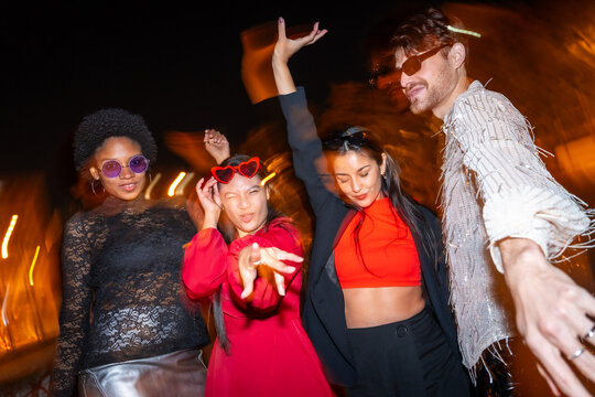 Fashion multi-ethnic friends dancing in the street at night