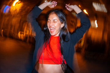 Excited woman dancing alone in the city street at night