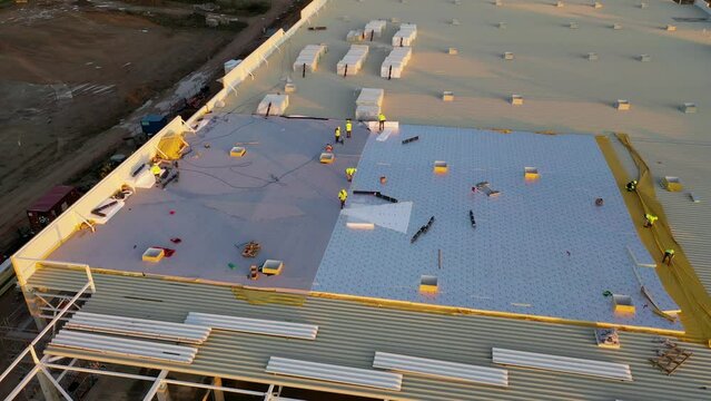 Drone footage of constructions site of large commercial building and construction workers building the rooftop during autumn morning