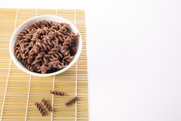 Organic cooked Buckwheat Fusilli pasta on white background. Wholegrain gluten free noodles. Healthy food concept